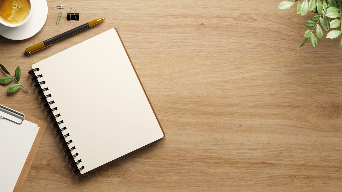 Top view of blank white page of diary notebook with pen and paper clips aside coffee on wooden table.